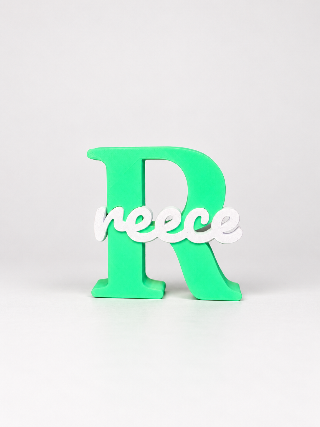 Small personalised 3D printed name and initial sign with green R and white Reece lettering